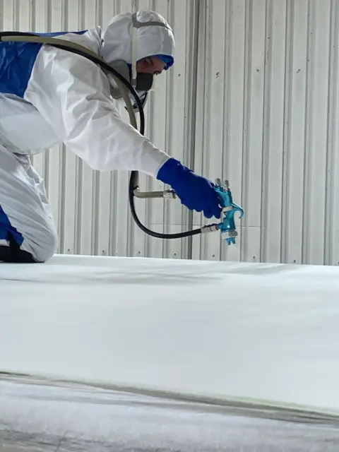 A close up of PolyFrost being applied by a worker to a trailer roof